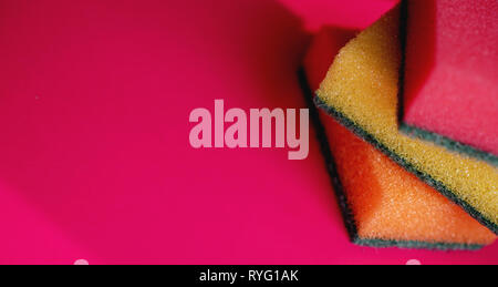 Sponges - close-up. Household cleaning concept. Colorful orange pink yellow sponges on pink background, soft focus, copy text. Stock Photo