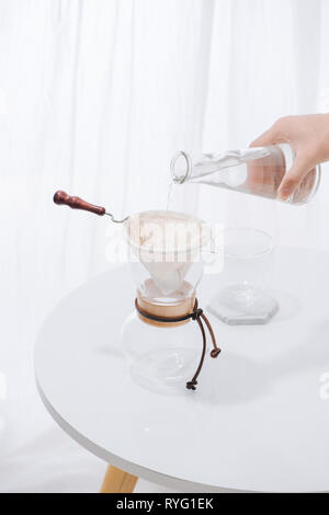 Pouring Water to the Coffee Pot on White Wall and White Table, Manual Brew, Hand Drip Coffee Stock Photo