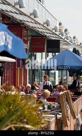 People sitting outside restaurants in Brighton Marina, Sussex, England. Stock Photo