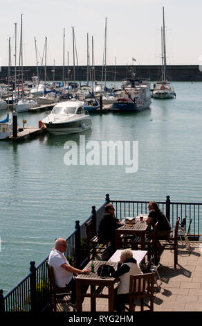 People sitting outside restaurants in Brighton Marina, Sussex, England. Stock Photo