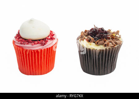 Cupcake in red paper case with pink frosting and raspberry on top and chocolate black forest fairy cake on white, selective focus Stock Photo