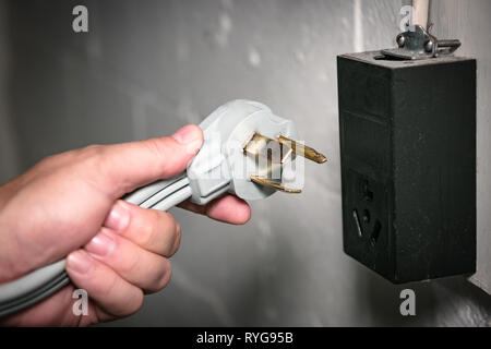 Closeup view of 3 prong electric dryer cord and 240 volt socket. Stock Photo