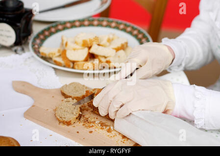 Cutting baguette in slices on wooden cutting board Stock Photo