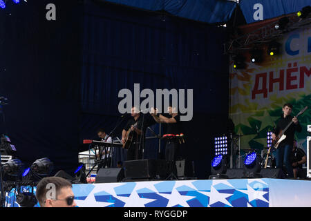 Band red silhouette crowd. Popular singer on stage in front of crowd on scene in night club. Bright stage lighting. Crowded dance floor Russia Berezni Stock Photo