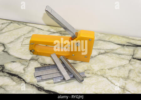 Large stapler and staples for construction work on white Stock Photo
