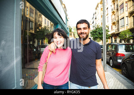 Happy and attractive young couple laughing while walking on the city street Stock Photo