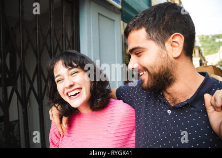 Happy and attractive young couple laughing while walking on the city street Stock Photo
