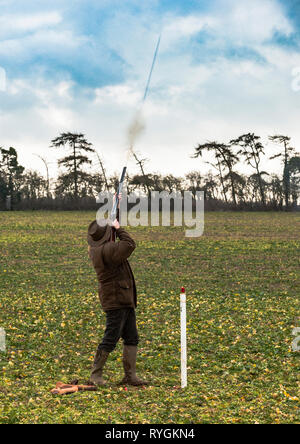 A man who has just fired a shotgun and the column of shot can be seen leaving the end of the barrel Stock Photo