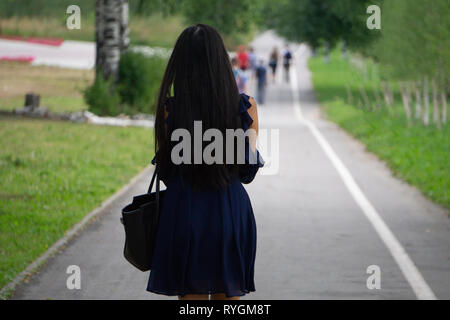 Side view of a Caucasian Businesswoman walking on city street in front of modern marble wall Stock Photo