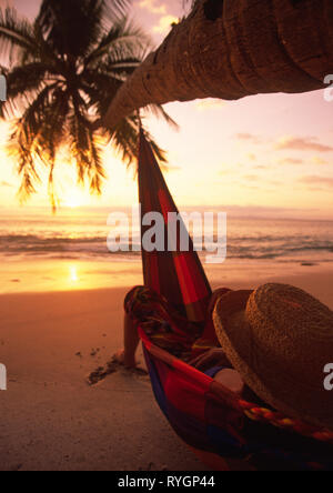 a woman in a hammoch on a Costa Rican beach under a palm tree 2002 Stock Photo