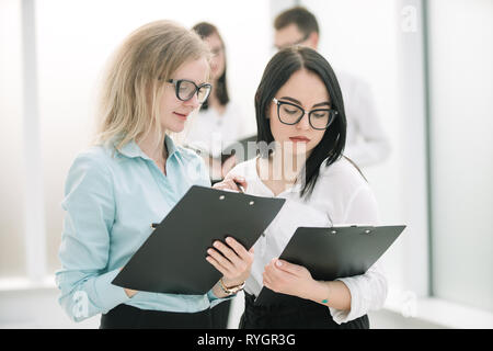 two business women discussing business documents standing in the office. Stock Photo