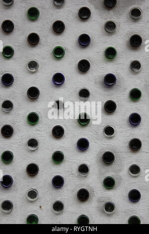 Wall design of colored glass wine bottles stuck in the concrete wall. Stock Photo