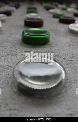 Wall design of colored glass wine bottles stuck in the concrete wall. Stock Photo