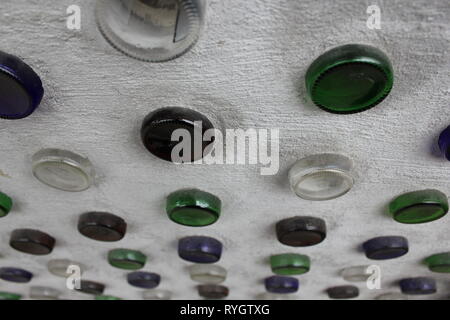 Wall design of colored glass wine bottles stuck in the concrete wall. Stock Photo