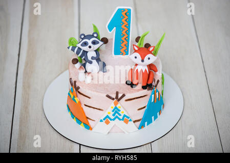 Close up of cake from pastry chef for birthday 1 year old baby. Children's cake is decorated with animal figures, wigwam and number one Stock Photo