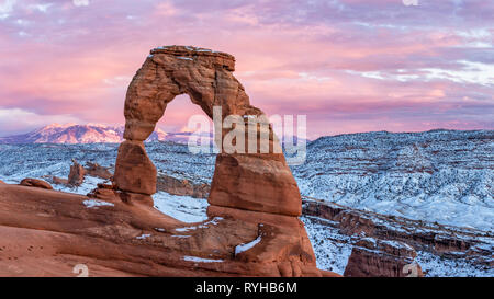 A colorful sunset lights up the La Sal Mountains behind iconic Delicate Arch in after a Febraury 2019 snowstorm in Arches National Park, Moab, Utah. Stock Photo