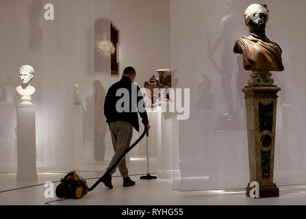 Maastricht, Netherlands. 13th Mar, 2019. A man sucks dust between sculptures at the Tomasso Brothers Gallery stand at the TEFAF art fair. The fair will take place from 16 to 24 March 2019 and is considered the world's most important fair for ancient art. (to dpa 'Colonial debate catches up with art fair TEFAF' from 14.03.2019) Credit: Oliver Berg/dpa - ATTENTION: Only for editorial use in connection with the current reporting on the art fair TEFAF 2019/dpa/Alamy Live News Stock Photo