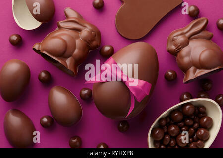Easter composition with chocolate eggs and bunnies on purple background, holiday concept Stock Photo