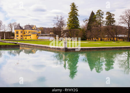 Hellbrunn Palace (Schloss Hellbrunn) and park on a beautiful spring day. Sculptures and trees reflecting in waters of  pool.  Salzburg, Austria. Stock Photo