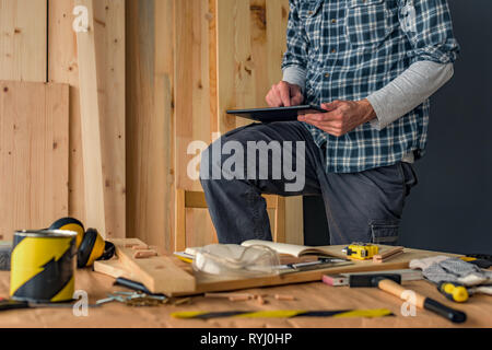 Carpenter using digital tablet in small business woodwork workshop for planning a new DIY project Stock Photo