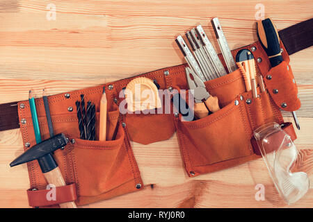 Organized handyman tool belt on work desk Stock Photo
