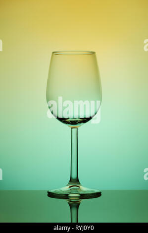 Still life. Glass to clear. Wine glass on a high and thin stalk on a colored background. Stock Photo