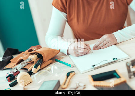 Self employed female carpenter writing project notes on clipboard note paper, selective focus Stock Photo