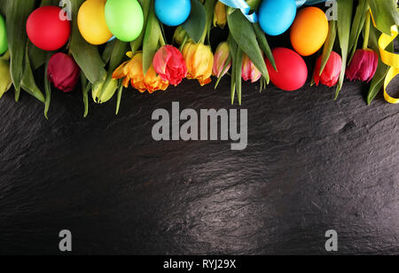 Easter eggs and colorful tulips on rustic table Stock Photo