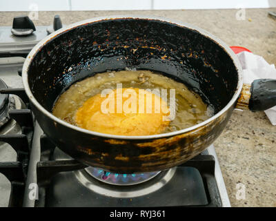 an arepa been fried in a pan in a gas stove covered by oil typical food of the caribbean coast of colombia Stock Photo