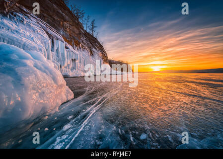 Sunset sky with natural breaking ice over frozen water on Lake Baikal, Siberia, Russia. Stock Photo