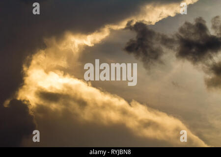 Dark clouds with orange sunset light on sky Stock Photo