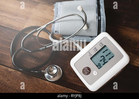 Stethoscope and Sphygmomanometer an electronic blood pressure monitor on a wooden table. concept of health and medical Stock Photo