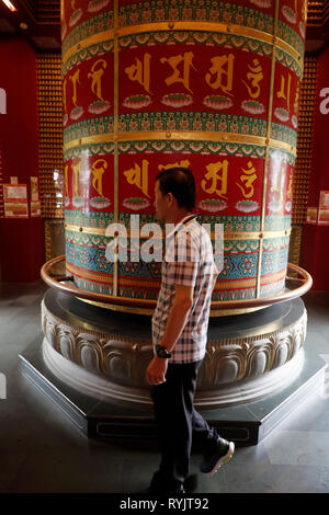 Buddha Tooth Relic Temple in Chinatown. Viarocana Buddha prayer wheel.  Worshipper. Singapore. Stock Photo