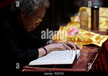 Buddha Tooth Relic Temple in Chinatown. Woman at  Buddhist ceremony.  Singapore. Stock Photo