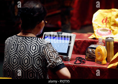 Buddha Tooth Relic Temple in Chinatown. Woman at  Buddhist ceremony.  Singapore. Stock Photo
