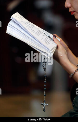 christian woman reading the bible with prayer beads.  St Philip church ( Huyen Sy Church ).  Ho Chi Minh City.  Vietnam.