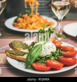 Italian dinner at bistrot with caprese and pasta, square crop Stock Photo