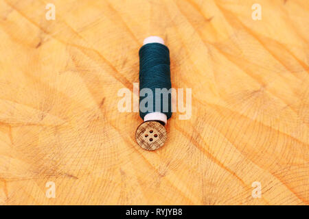 Photo of blue Sewing thread and button. Isolated on the yellow background. Stock Photo