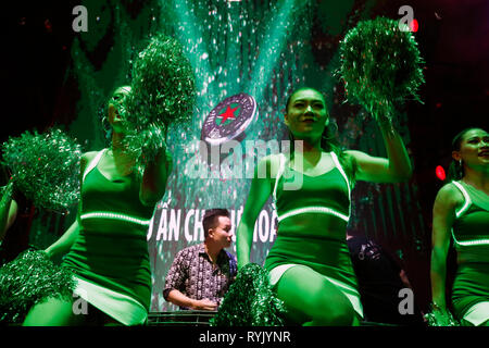 DJ on stage and Heineken girls gesturing to crowd dancing in nightclub.  Ho Chi Minh City. Vietnam. Stock Photo