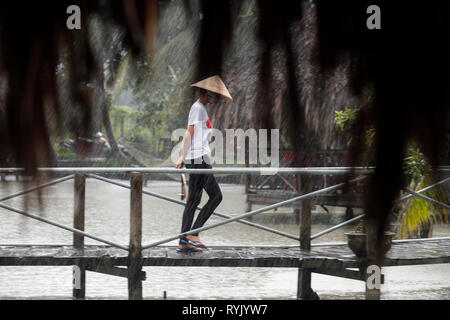 Rainy season.  Vietnamese woman with conical hat under heavy rain.  Can Tho. Vietnam. Stock Photo