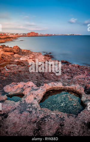 Beautiful long exposure sunset shot of a seascape view of Paphos Medieval Castle and sea coast Stock Photo