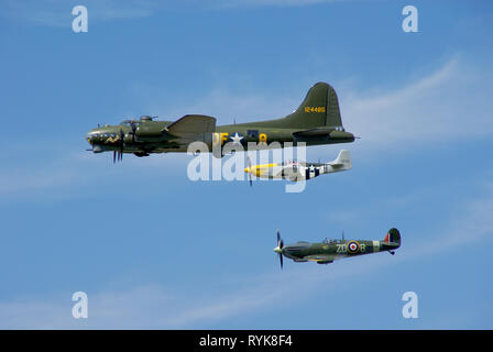 Boeing B-17 Flying Fortress bomber plane with escort fighters. Second World War planes. Supermarine Spitfire and North American P-51 Mustang. Flying Stock Photo