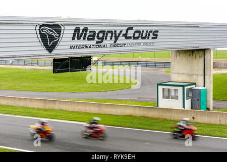 Three motorbikes running on the track of the racing circuit of Nevers Magny-Cours during a test session organized by a motorcycle brand. Stock Photo