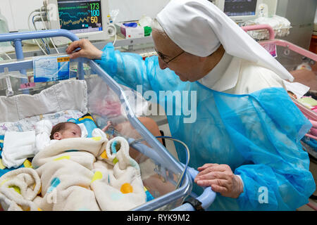 St Vincent de Paul hospital, run by the Daughters of Charity catholic missionaries in Nazareth, Israel. Neonatology ward. Nun looking at a premature b Stock Photo