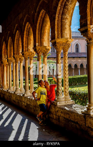 12-year-old boy with his mother in the cloister of Monreale cathedral, Sicily (Italy). Stock Photo