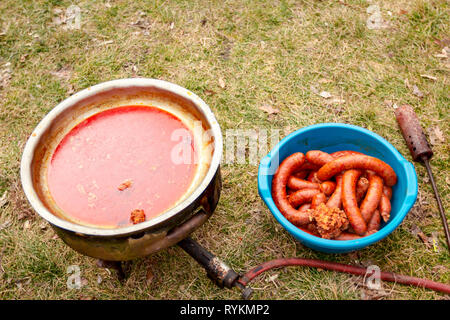 View from above on baked homemade pork sausages placed in the plastic bowl next to barbecue grill, metal griddle. Stock Photo