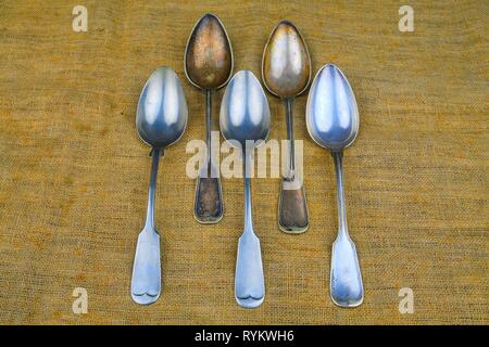 Old spoons on a bagging background. Five vintage spoons. Top view. Free space for text. Stock Photo