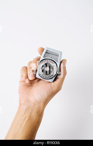 closeup of a caucasian man with an old analog light meter in his hand, against a white background with a blank space on top Stock Photo