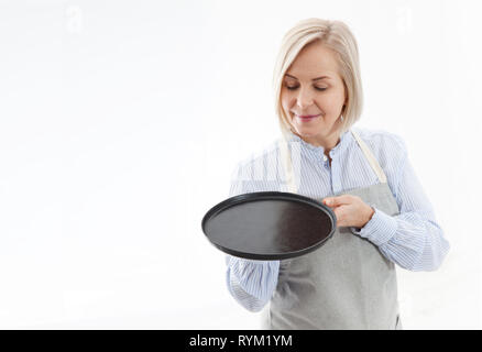 Kitchen woman waitress gives empty black plate for your advertising products isolated on white background. Mock up for use Stock Photo