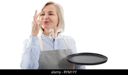 Chef woman showing sign for delicious. Female chef in uniform with perfect sign holding empty plate. Satisfied chef, cook or baker gesturing excellent. Cook with taste approval gesture. Mock up. Stock Photo